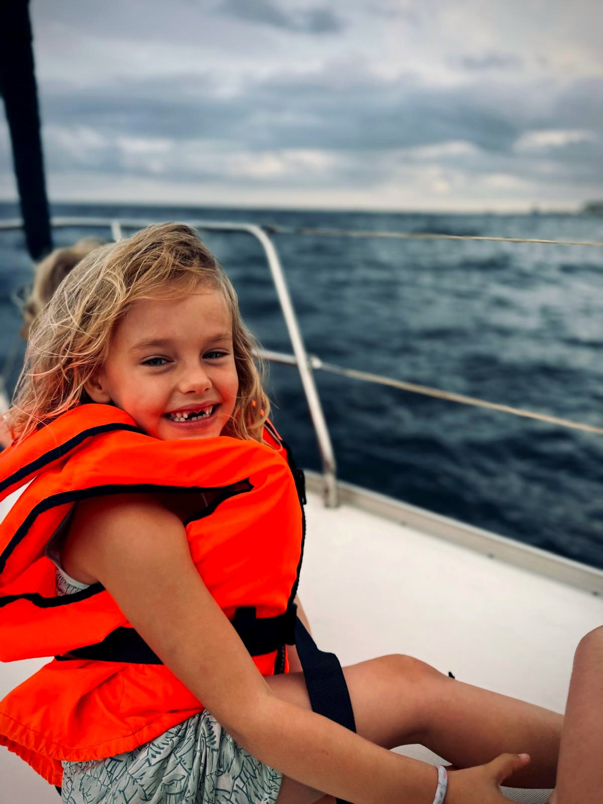 Smiling child in a life jacket during a family sailing trip