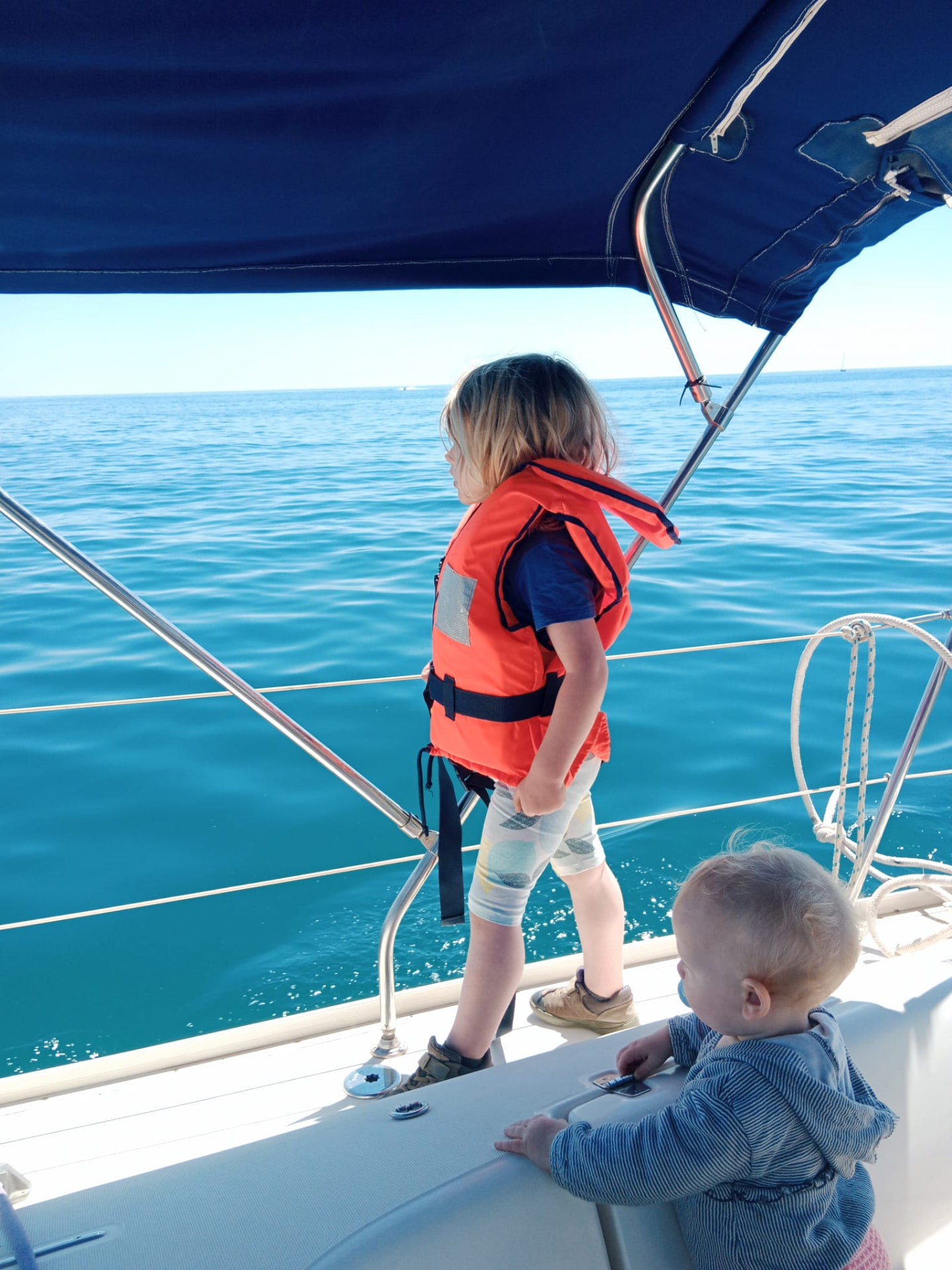 Two children looking out at the sea from a family sailboat near Barcelona