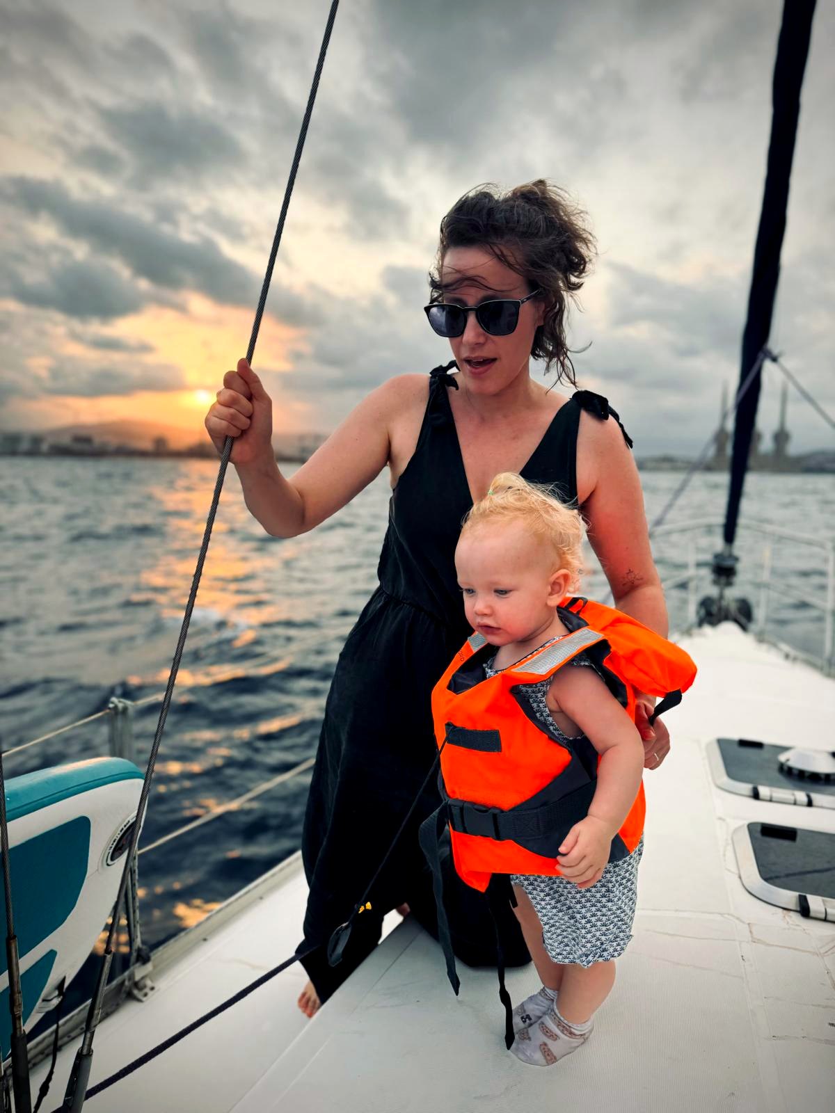 Mother sailing with a young child wearing a life jacket near Barcelona