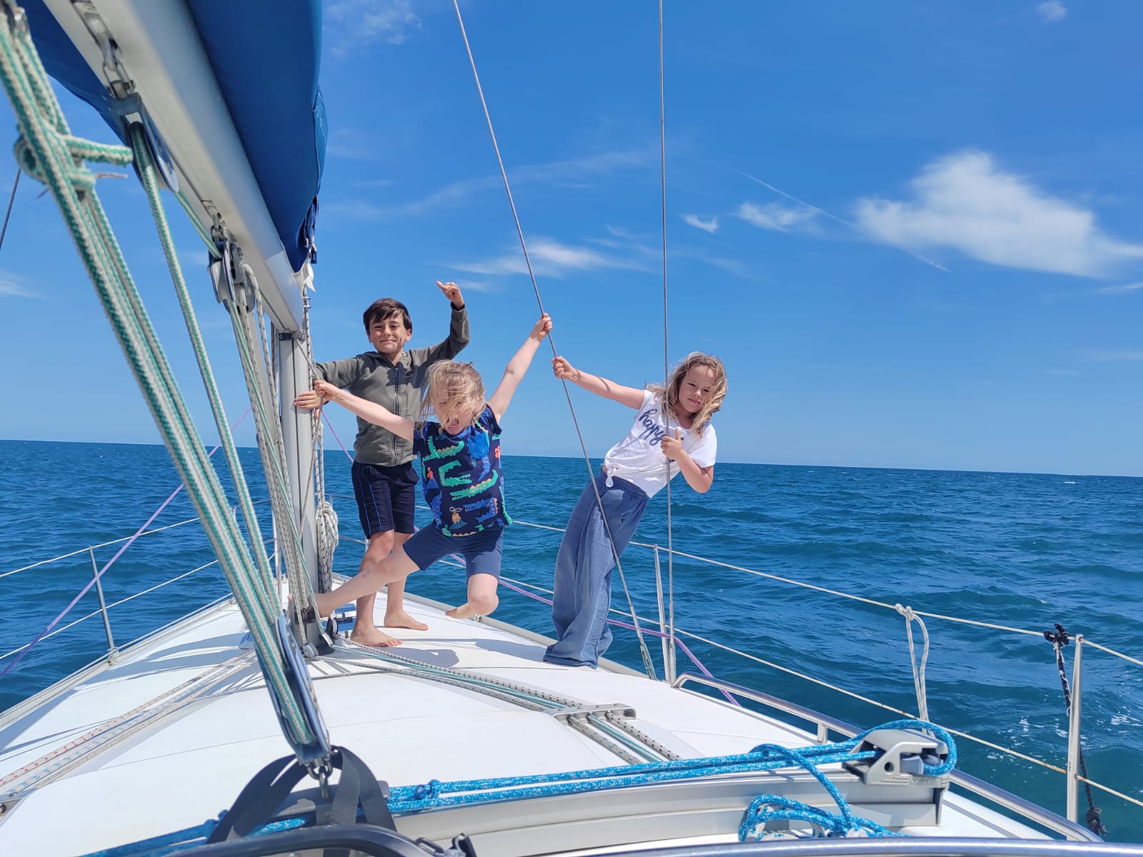 Three children enjoying a sailing trip on a family sailboat near Barcelona