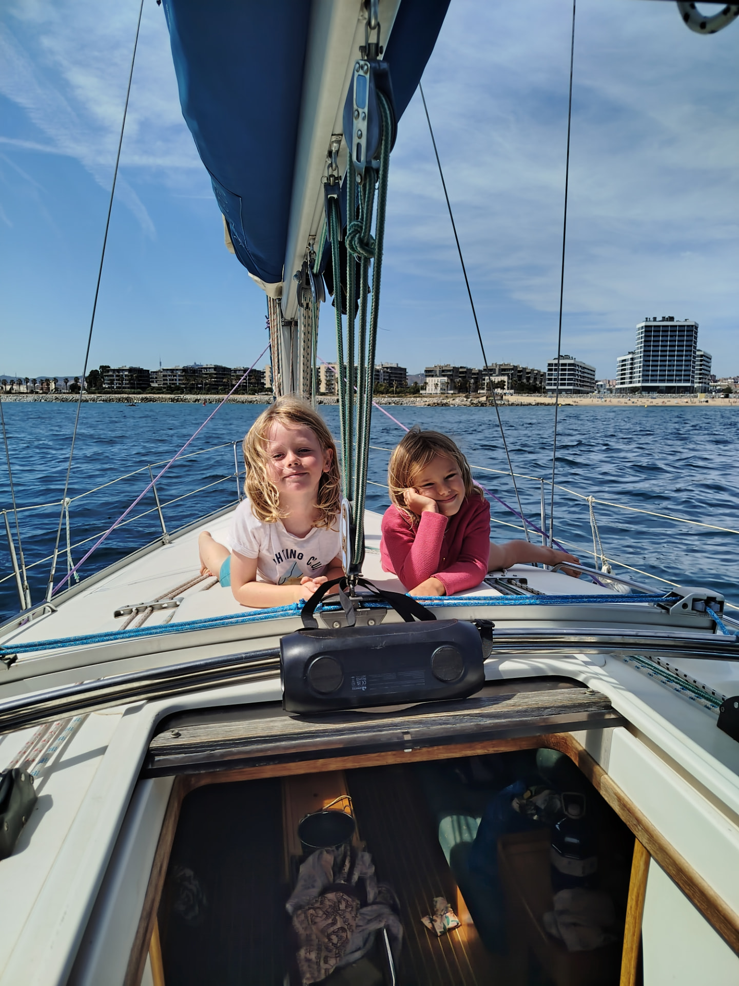 Two children relaxing on the deck of a family sailboat near Barcelona