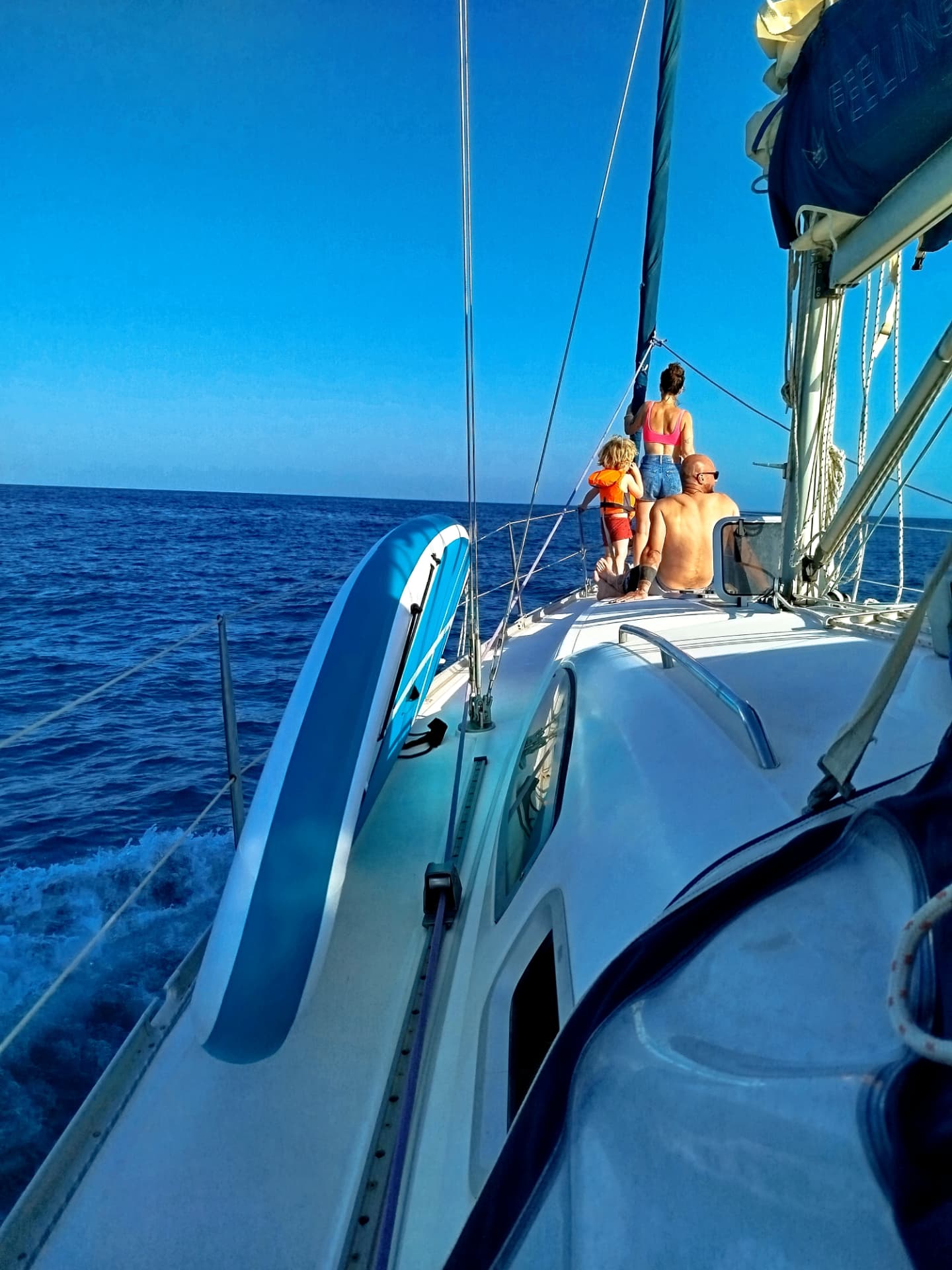 Family standing together on the bow of a sailboat during a family boat trip in Barcelona